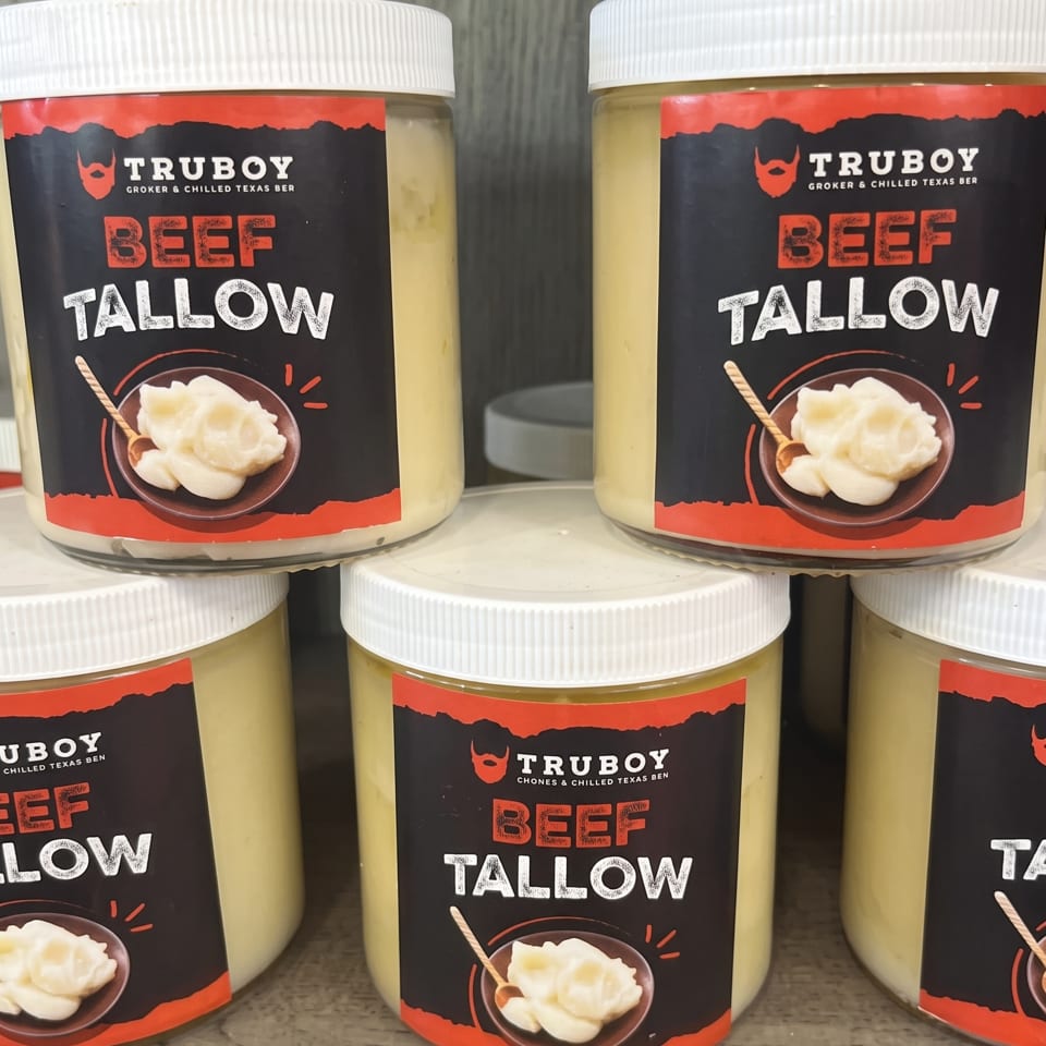 Several jars of Truboy beef tallow with white lids and red-and-black labels arranged on a shelf.